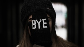 A photo of a woman with a gloved hand covering her face